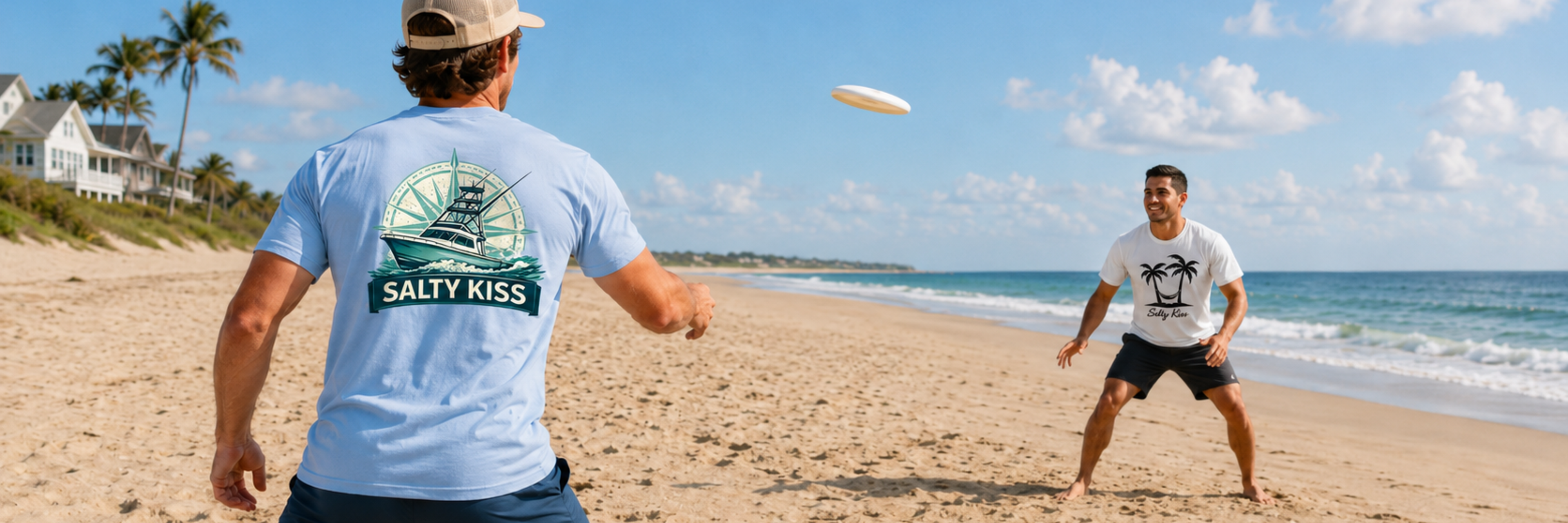 Salty Kiss men’s coastal graphic tees worn during a beach frisbee game near ocean waves.