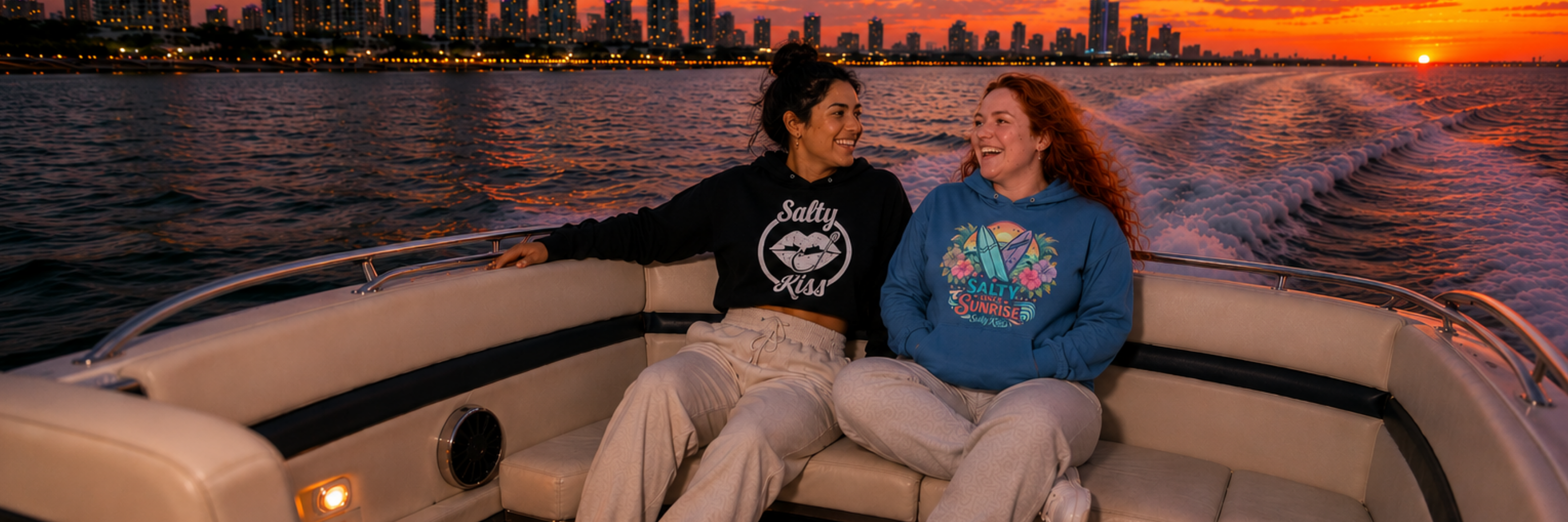 Salty Kiss women’s coastal graphic hoodies worn on a sunset boat ride by the water.