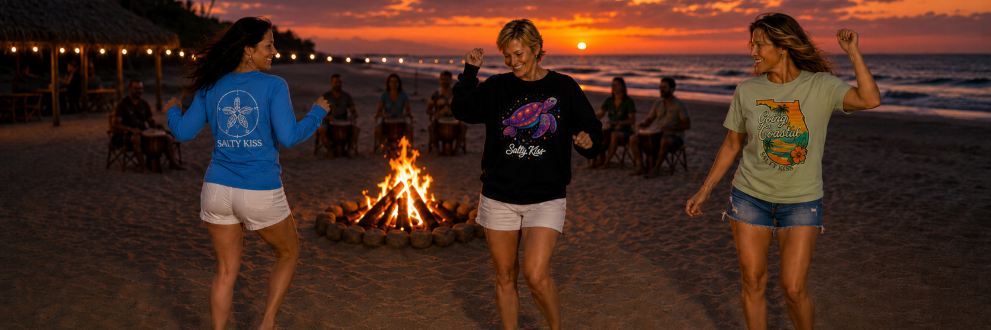 Salty Kiss women’s coastal graphic tees, performance shirts, and sweatshirt worn at a sunset beach bonfire.