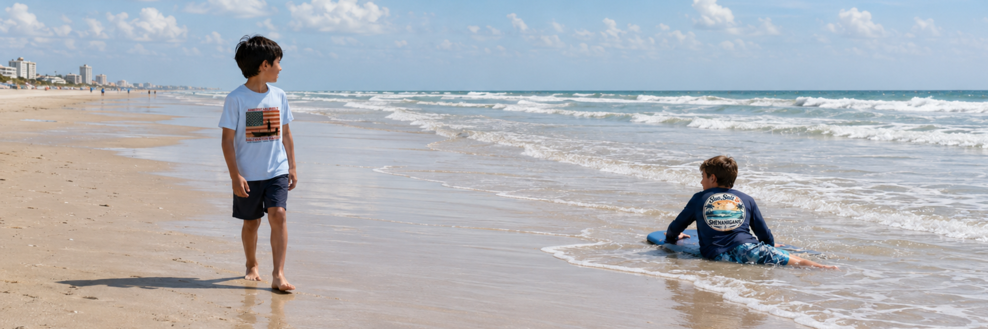 Youth boys beach lifestyle image featuring a youth boy in a light blue American Built Saltwater Raised t-shirt watching his older brother boogie board in a navy Sun, Salt and Shenanigans long sleeve shirt on Daytona Beach.